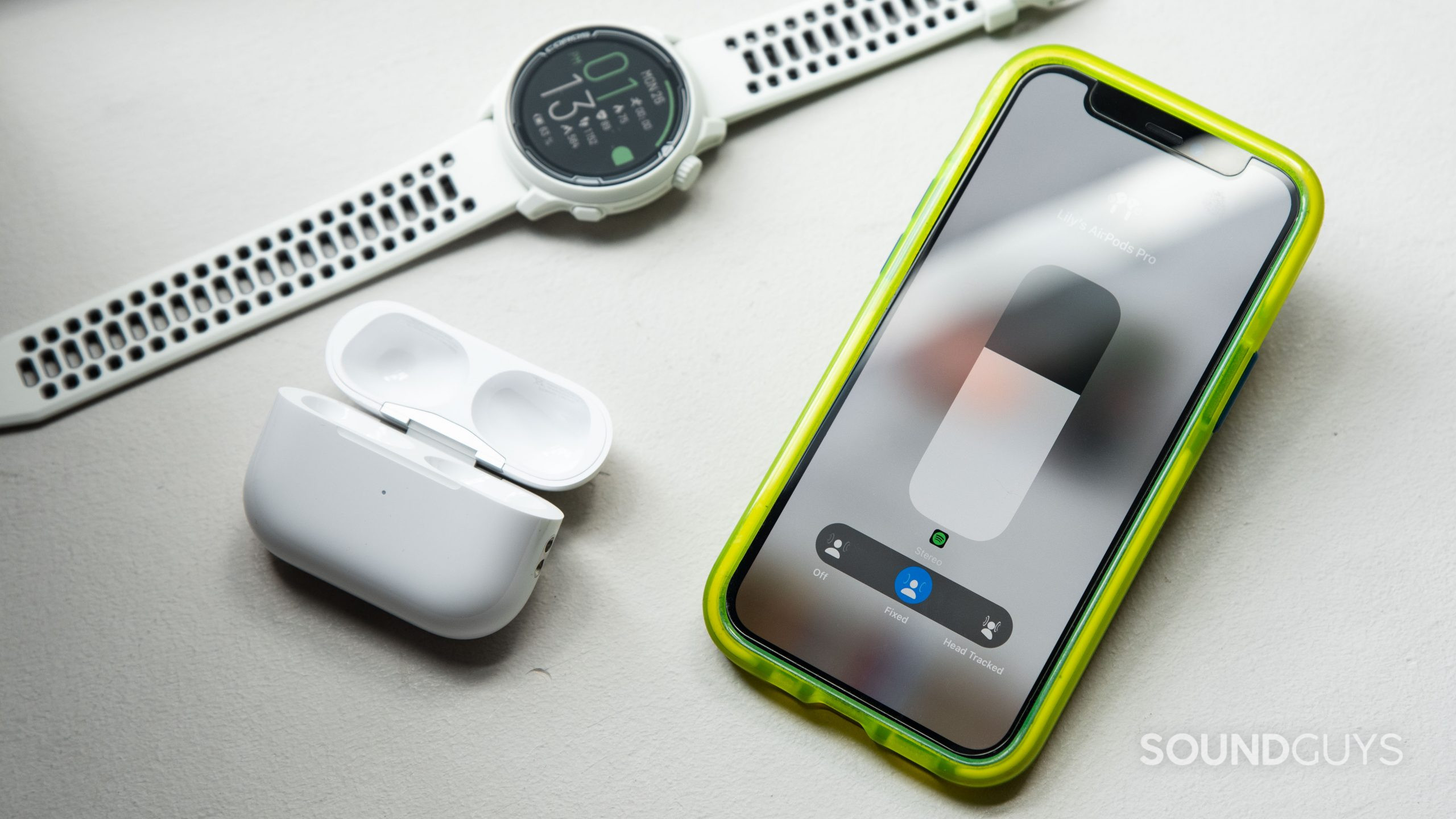 Apple AirPods Pro (2nd generation) true wireless earbuds spatial audio settings An iPhone 12 mini displays the AirPods Pro (2nd generation) spatial audio modes with the case and a smart watch next to it.