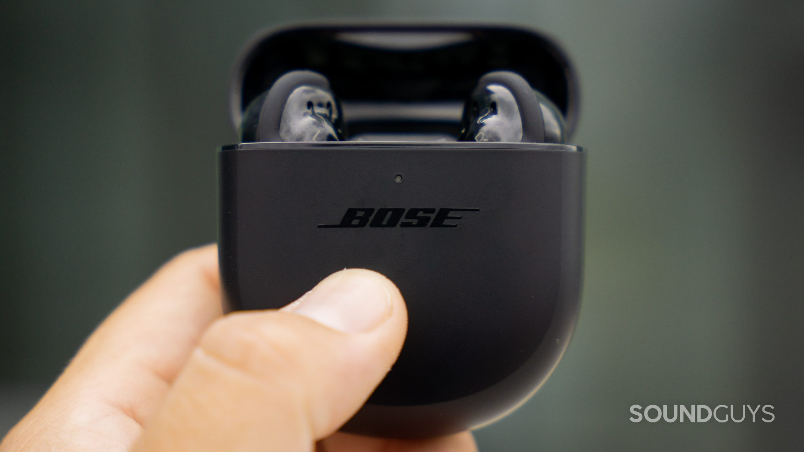 Bose QuietComfort Earbuds II true wireless noise canceling case earbuds reveal handheld A hand holds the Bose QuietComfort Earbuds II case, which is open and contains the earbuds.