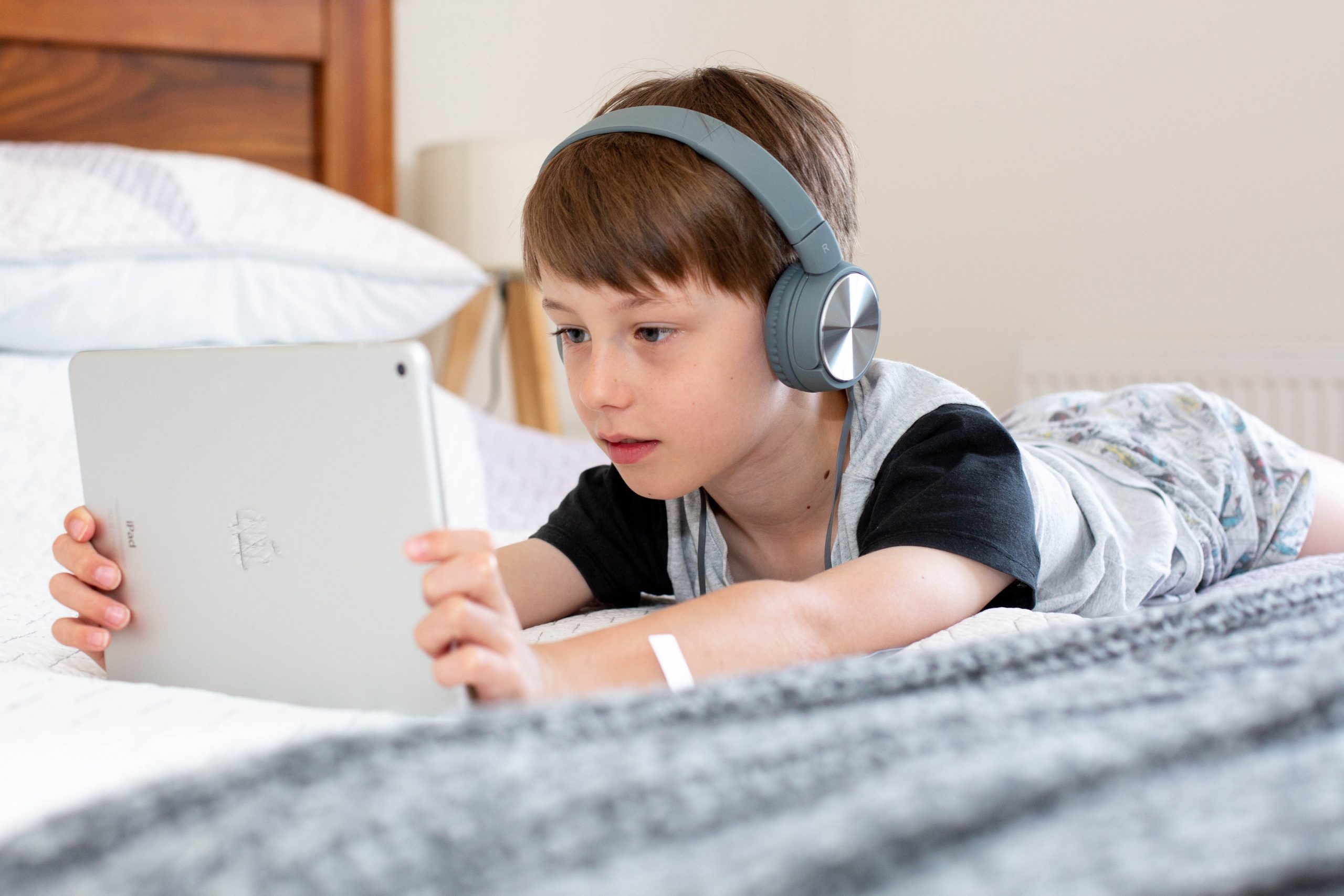 emily-wade-DfqQKk2qqaY-unsplash Boy wearing headphones watching a tablet