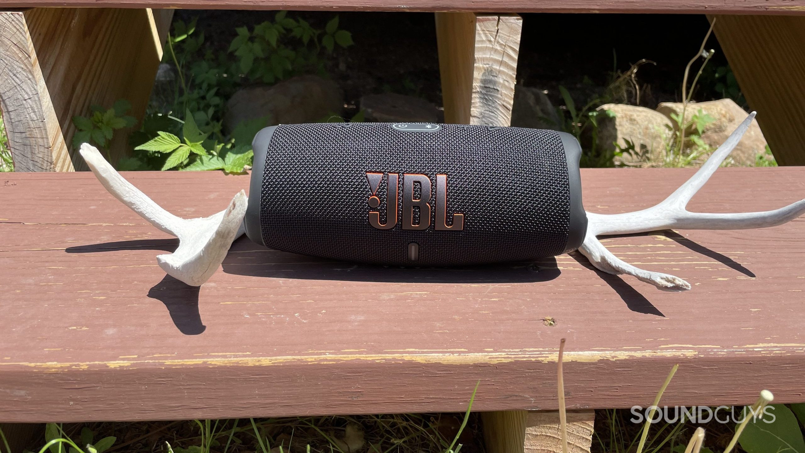 JBL Charge 5 bench JBL Charge 5 resting on a wooden step with deer antlers next to it.