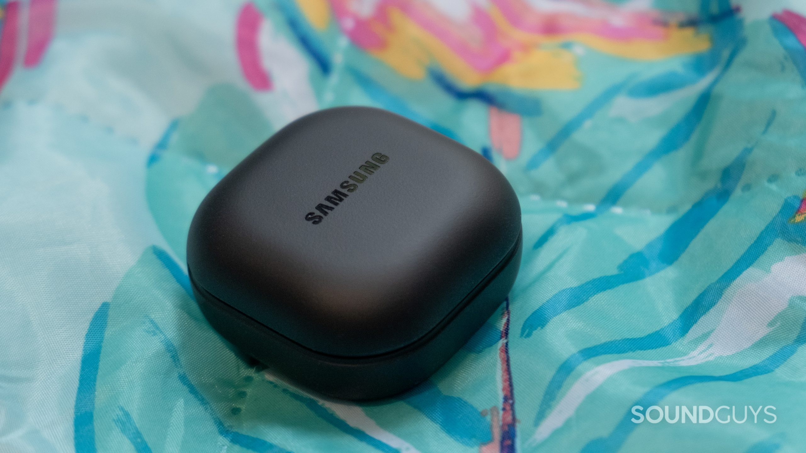 samsung-galaxy-buds-2-pro-case The closed back case of the Samsung Galaxy Buds 2 Pro rests on a colorful tropical themed blanket.