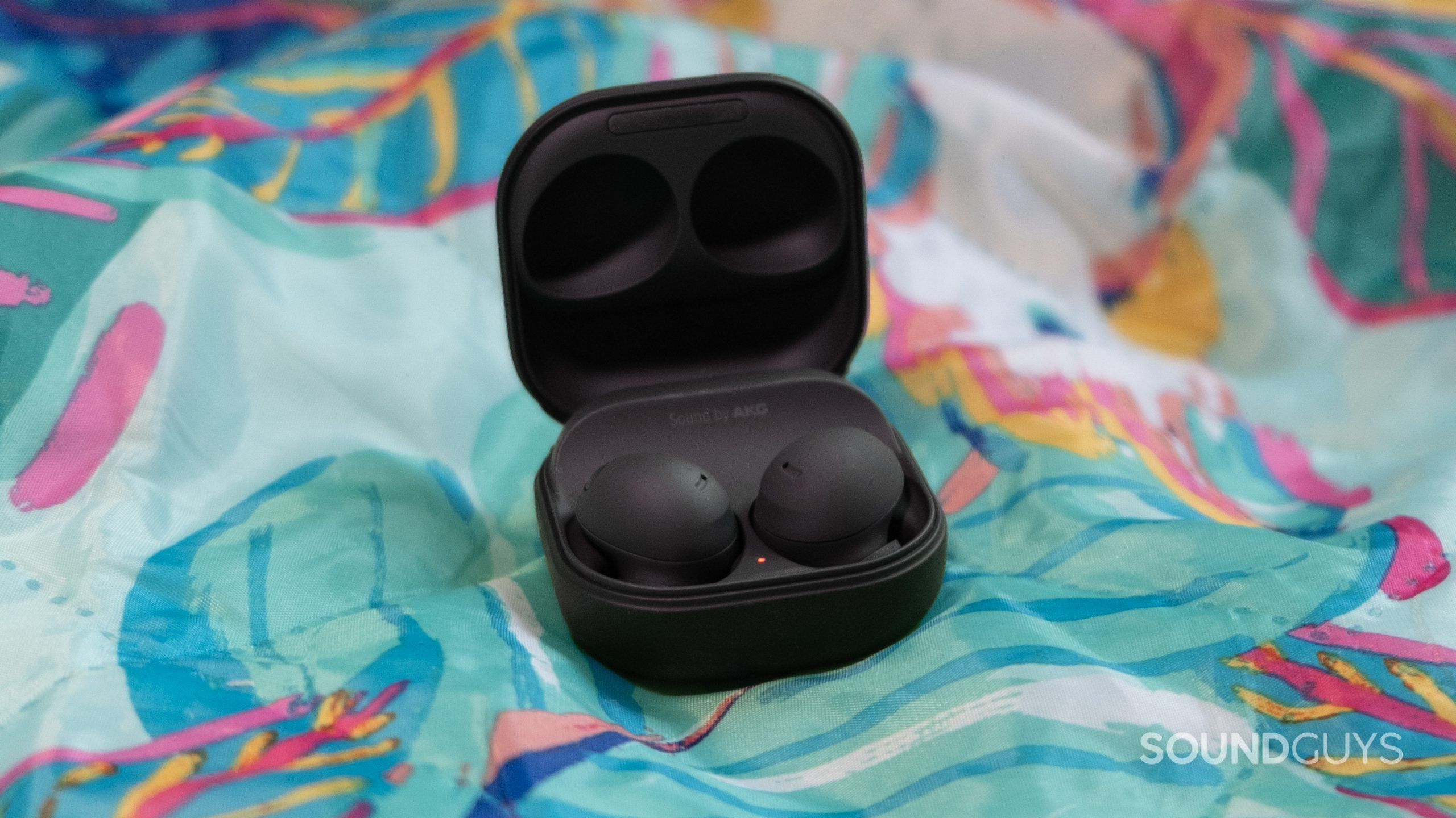 samsung-galaxy-buds-2-pro-center-shot On a tropical themed outdoor blanket the open case of the Samsung Galaxy Buds 2 Pro rests with the lid open.