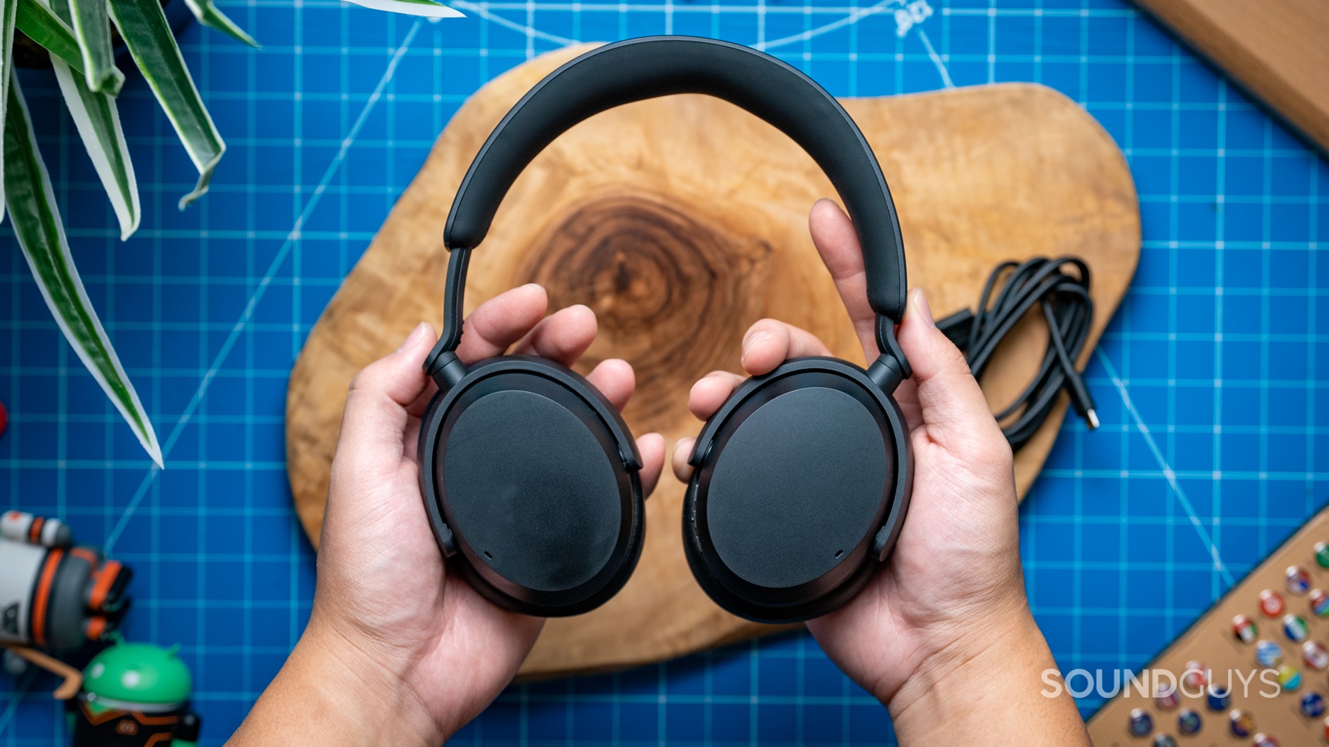Sennheiser-Accentum-Wireless-Featured-Image-#1 The Sennheiser ACCENTUM Wireless held above wood.