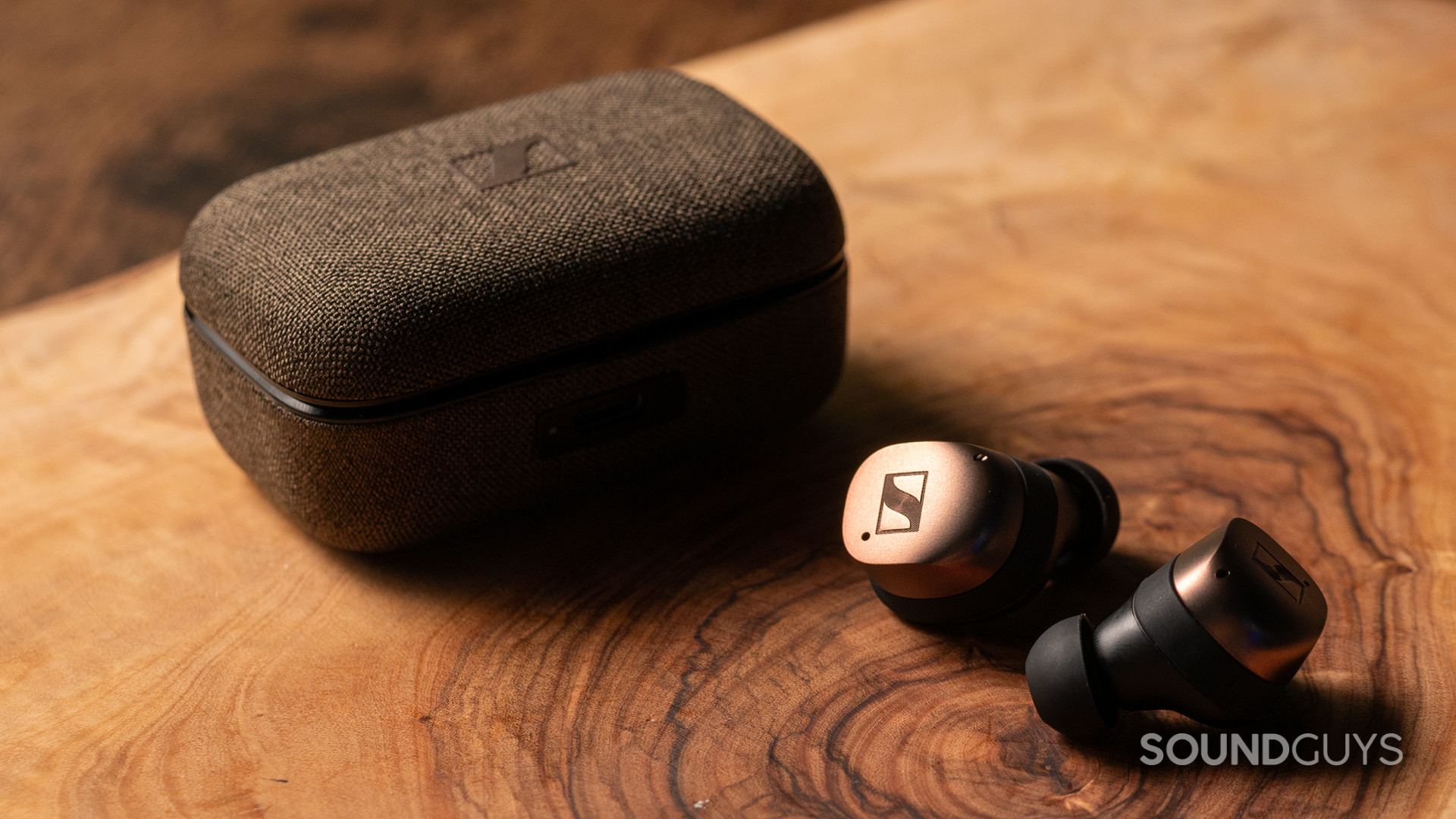 sennheiser-momentum-true-wireless-4-hero A photo of the Sennheiser MOMENTUM True Wireless 4 on a wooden table, outside of their charging case.