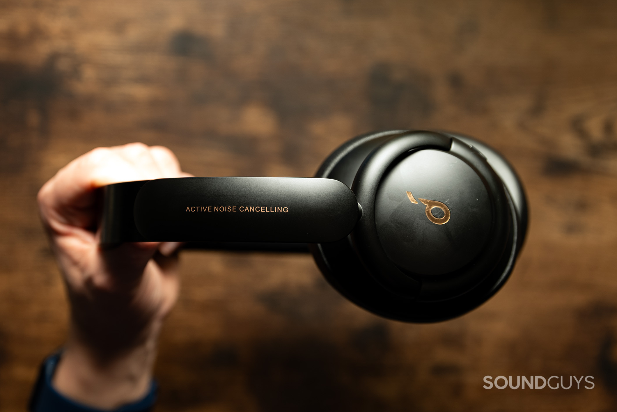 Soundcore Life Q30 side profile Anker Soundcore Life Q30 headphones held in a hand above a wood table.